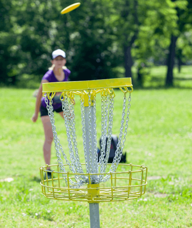 A girl throws a disc into the air. A woman throws a disc in the park.<br />